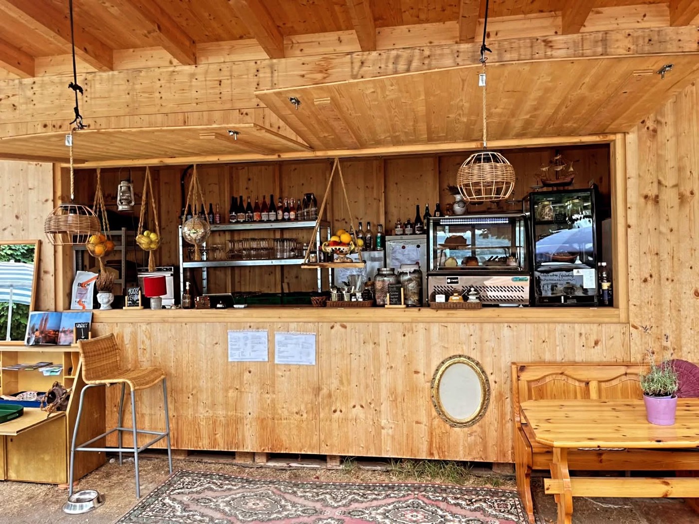 Innenraum des Seeliebi-Holzpavillons mit Theke, Regalen voller Schweizer Naturweine, Gläsern und einer Vitrine